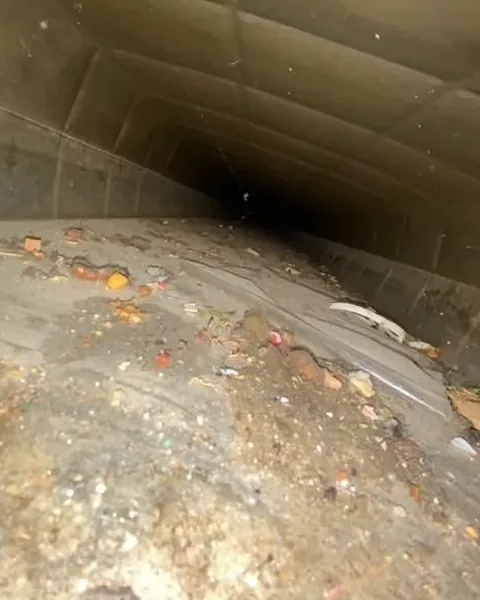 Before: Debris and dirt on the floor of a supply duct
